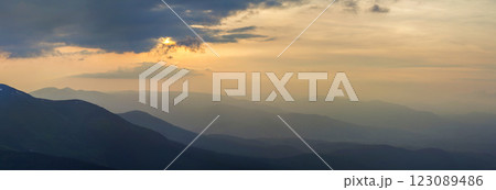 Wide panorama, fantastic view of covered with morning mist green Carpathian mountains at dawn under dark clouds and light pink sky before sunrise. Beauty of nature, tourism and traveling concept. Wide panorama, fantastic view of covered with morning mist green Carpathian mountains at dawn under dark clouds and light pink sky before sunrise. Beauty of nature, tourism and traveling concept. 123089486