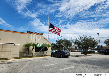 USA national flag waving lowered to half mast on wind against blue sky. American stars and stripes spangled banner as symbol of democracy 123089563