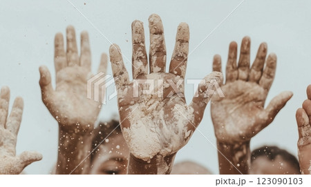 Close-up of African children's hands covered in flour, raised playfully against a bright sky. A concept of childhood, creativity, and outdoor fun 123090103