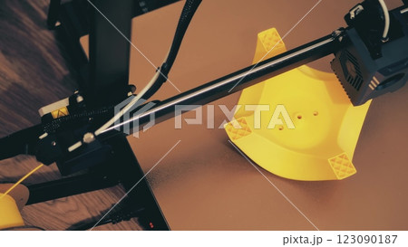 A plastic filament 3d printer prints the yellow model, close-up view from above 123090187