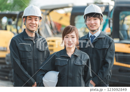 重機の前にいる作業着姿の建設業・建築業の作業員男女 123092849