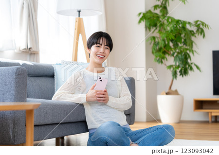 部屋でスマホを操作する女性 部屋でスマホを操作する女性 123093042