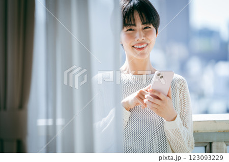 部屋でスマホを操作する女性 123093229