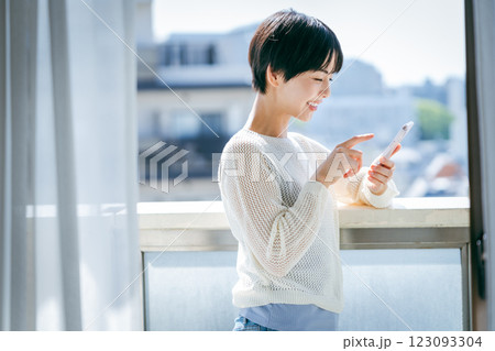 部屋でスマホを操作する女性 123093304
