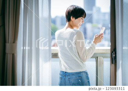 部屋でスマホを操作する女性 123093311