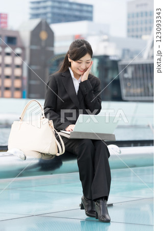 屋外でノートパソコンを見て微笑むビジネスウーマン　名古屋　栄　OASIS21　水の宇宙船にて 123093343