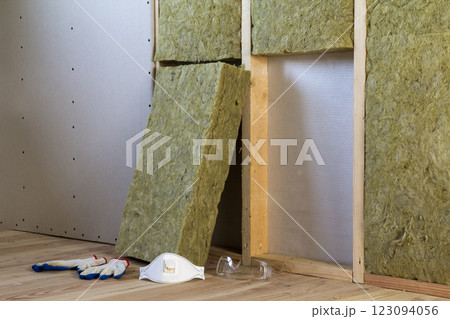 Rock wool and fiberglass insulation staff material for cold barrier. Tools for work with glass wool: protective goggles, glasses and mask. Warm home, economy, construction and renovation concept. Rock wool and fiberglass insulation staff material for cold barrier. Tools for work with glass wool: protective goggles, glasses and mask. Warm home, economy, construction and renovation concept. 123094056