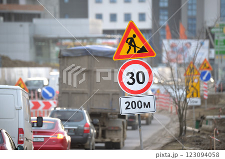 Roadworks warning traffic signs of construction work on city street and slowly moving cars Roadworks warning traffic signs of construction work on city street and slowly moving cars 123094058
