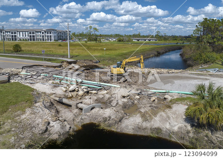 Road construction. Excavator repairing destroyed bridge after hurricane flooding water washed away asphalt in Florida. Construction equipment at roadwork site 123094099