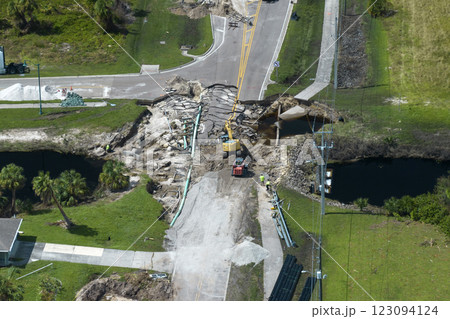 Repair of destroyed bridge after hurricane flood in Florida. Reconstruction of damaged road after flooding water washed away asphalt. Construction equipment at roadwork site 123094124