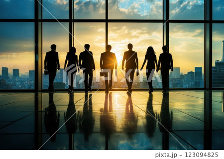 夕日を背にしたビジネスチームが高層ビルの窓辺に立つシルエット（企業の成長・リーダーシップ・チームワー 123094825