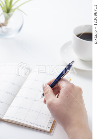 スケジュール帳に記入する女性の手 123096711