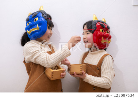 節分の日に鬼の面をつけて楽しむ姉妹の豆まき 節分の日に鬼の面をつけて楽しむ姉妹の豆まき 123097534
