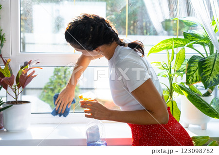 Woman manually washes the window of house with rag cleaner and mop inside the interior with home plants on windowsill. Restoring order and cleanliness in the spring, cleaning servise Woman manually washes the window of house with rag cleaner and mop inside the interior with home plants on windowsill. Restoring order and cleanliness in the spring, cleaning servise 123098782
