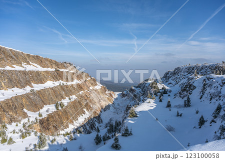 Snow blankets the Stanislaw Quartz Mine in the Izerskie Garby region, creating a serene winter landscape. The rugged cliffs and scattered trees stand out against the clear blue sky. Snow blankets the Stanislaw Quartz Mine in the Izerskie Garby region, creating a serene winter landscape. The rugged cliffs and scattered trees stand out against the clear blue sky. 123100058
