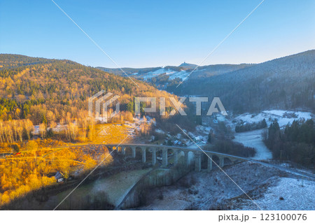A stunning winter sunset casts warm hues over the railway stone bridge in Novina, surrounded by serene valleys and distant Jested Mountain, creating a picturesque landscape. A stunning winter sunset casts warm hues over the railway stone bridge in Novina, surrounded by serene valleys and distant Jested Mountain, creating a picturesque landscape. 123100076