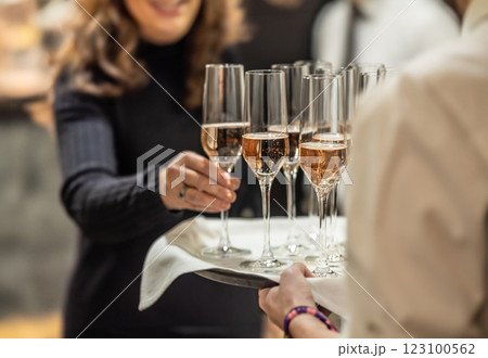 Young waiter holding a tray with champagne or prosecco at a wedding or gala event and offering guests a welcome drink Young waiter holding a tray with champagne or prosecco at a wedding or gala event and offering guests a welcome drink 123100562