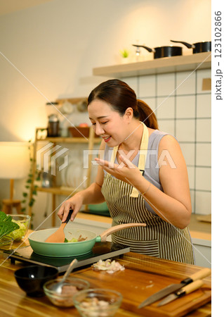 Happy adult woman wearing apron cooking healthy meal in kitchen Happy adult woman wearing apron cooking healthy meal in kitchen 123102866