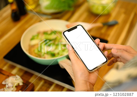 Close up woman checking her phone for recipe instructions while preparing a meal 123102887