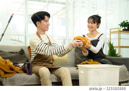 Cheerful young couple folding laundry together in a cozy living room Cheerful young couple folding laundry together in a cozy living room 123102888