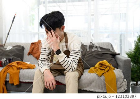 Tired and upset man sitting on couch in messy living room 123102897