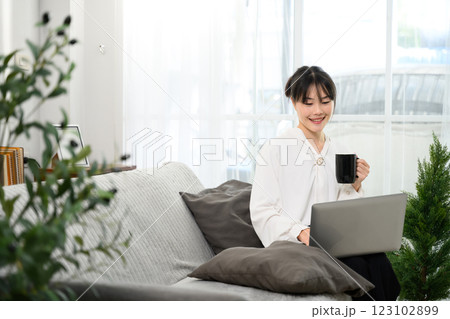 Cheerful asian woman sipping coffee and working on her laptop 123102899