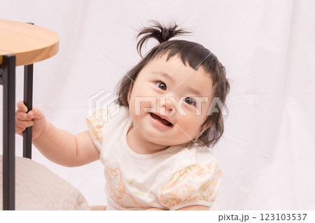 【テーブルでつかまり立ちをするツインテールの赤ちゃん】 123103537