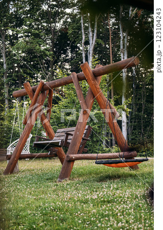 Wooden backyard swing set with natural surroundings, emphasizing relaxation, outdoor activities, and eco-friendly design in a rustic environment 123104243
