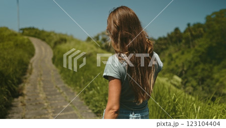 Long hair brunette girl walk green field meadow trail in Ubud, Bali island. Campuhan Ridge Walk scenery path picturesque hills. Outdoor lifestyle travel summer holiday vacation. Back view, 123104404