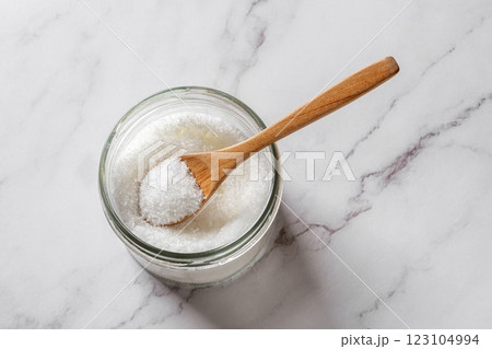 Full spoon in a jar of monosodium glutamate over kitchen marble counter. 123104994