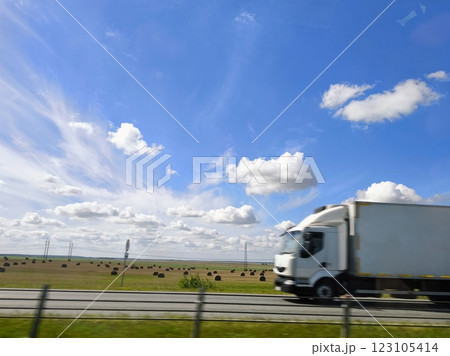 A car is moving on a high-speed highway, the view from the car window. The car is in motion on the highway against the background of a beautiful sky and fields. A car is moving on a high-speed highway, the view from the car window. The car is in motion on the highway against the background of a beautiful sky and fields. 123105414