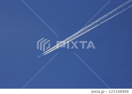 青空を二分するように飛行機雲が現れた。無風の上空には人々の夢をのせた飛行機 123106998