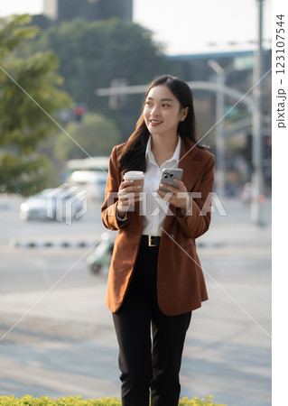 Portrait of a successful business woman using smartphone and digital tablet in front of modern business building. 123107544