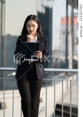 Business woman analyzing financial stats and graphs on paperwork in front of a modern office building. Business woman analyzing financial stats and graphs on paperwork in front of a modern office building. 123107565