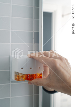 man plugs an air freshener in a bathroom man plugs an air freshener in a bathroom 123107795