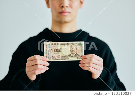 一万円札を持つ20代の若い男性 123110027