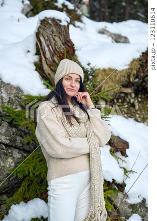 Serene Winter Portrait: Young Woman in Cream Sweater Contemplating Snowy Mountain Landscape with Evergreen Forest 123110614