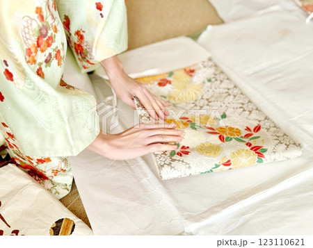 着物を着て帯をたとう紙に包む女性の手元 着物を着て帯をたとう紙に包む女性の手元 123110621