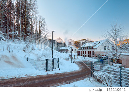 Serene winter mountain landscape with snow-covered pathway, modern apartment buildings, and majestic snow-capped peaks at sunrise. Serene Winter Wonderland Alpine Village Nestled Among Snowy Mountains Serene winter mountain landscape with snow-covered pathway, modern apartment buildings, and majestic snow-capped peaks at sunrise. Serene Winter Wonderland Alpine Village Nestled Among Snowy Mountains 123110641