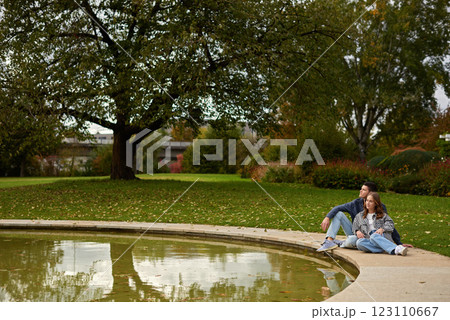 Autumn Serenity: Couple Relaxing by Reflective Pond Amidst Vibrant Fall Foliage and Ivy-Covered Architecture. Tranquil Garden Scene Captures Intimate Moment Against Backdrop of Colorful Autumn Leaves Autumn Serenity: Couple Relaxing by Reflective Pond Amidst Vibrant Fall Foliage and Ivy-Covered Architecture. Tranquil Garden Scene Captures Intimate Moment Against Backdrop of Colorful Autumn Leaves 123110667