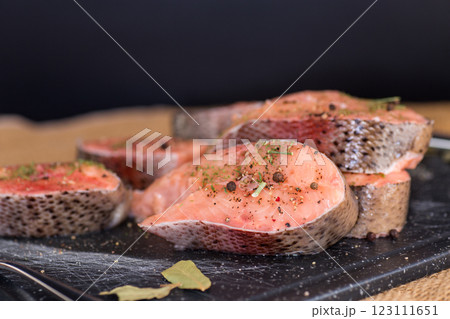 Natural piece of salmon with spices and herbs on a black background Natural piece of salmon with spices and herbs on a black background 123111651