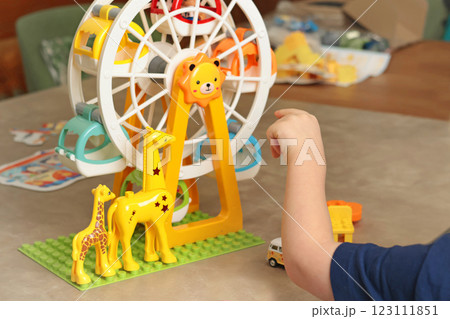 Child plays with a plastic constructor at home on table. Children and educational games. Animals of Africa and an amusement park. 123111851