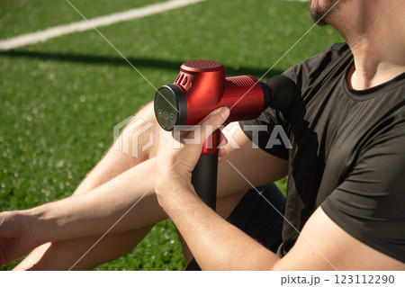 Man massaging hand with massage percussion device after workout. Applying therapeutic percussive massager gun. Close up. Man massaging hand with massage percussion device after workout. Applying therapeutic percussive massager gun. Close up. 123112290