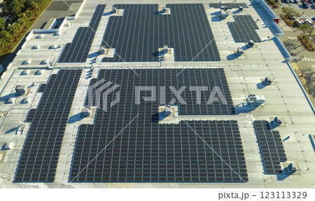 Production of sustainable energy. Aerial view of solar power plant with blue photovoltaic panels mounted on industrial building roof for producing green ecological electricity Production of sustainable energy. Aerial view of solar power plant with blue photovoltaic panels mounted on industrial building roof for producing green ecological electricity 123113329