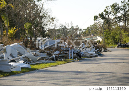 Piles of rubbish on street side from severely damaged houses after hurricane in Florida mobile home residential area. Consequences of natural disaster 123113360