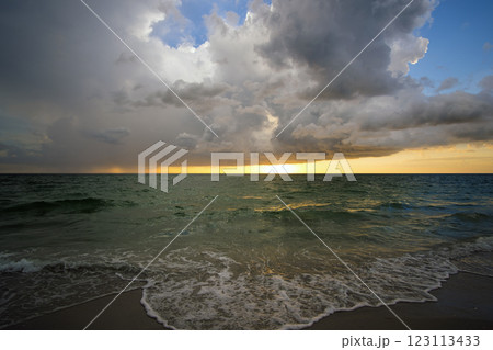 Ocean landscape with thunderstorm clouds over rough evening sea water waves crushing on sandy beach. Beautiful seascape at sunset 123113433
