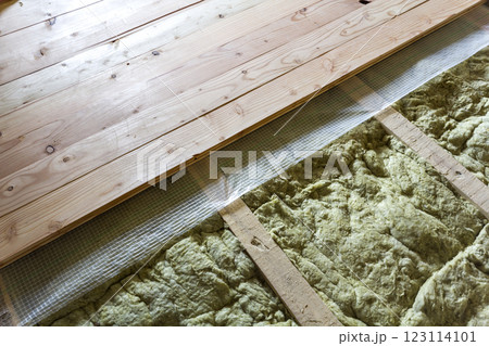 Installation of new floor of wooden natural planks and mineral wool insulation for isolation and keeping warmth. Construction, renovation, warm comfortable house concept. 123114101