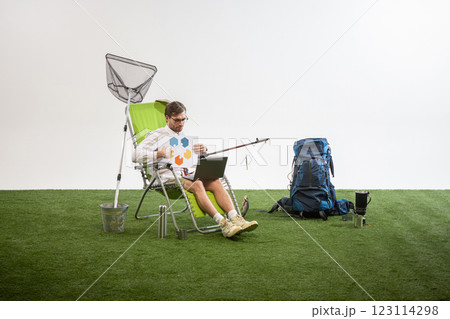 Businessman sitting on chair analyzing infographic while working on laptop against white studio background. Businessman sitting on chair analyzing infographic while working on laptop against white studio background. 123114298
