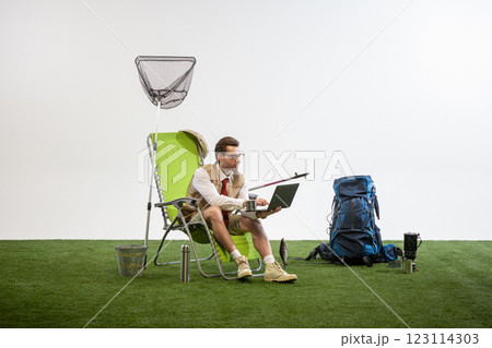 Businessman sitting on chair working on laptop while holding coffee cup against white studio background. Businessman sitting on chair working on laptop while holding coffee cup against white studio background. 123114303