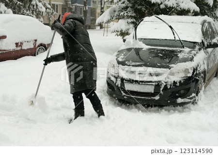 Woman Clearing Snow Near Car During Heavy Winter Snowfall Woman Clearing Snow Near Car During Heavy Winter Snowfall 123114590